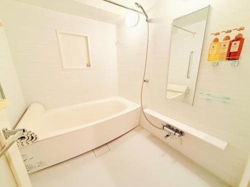a white bathroom with a tub and a mirror at 褚之屋一号 in Wada