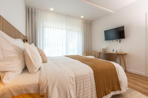 a bedroom with a large bed with a television on the wall at Ápice - by Azores Green Villas in São Vicente Ferreira