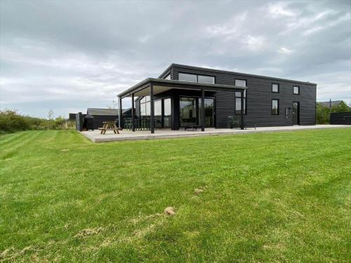 ein schwarzes Haus mit einem großen grünen Feld in der Unterkunft 30474 Odder - Strandvænget 64 in Odder