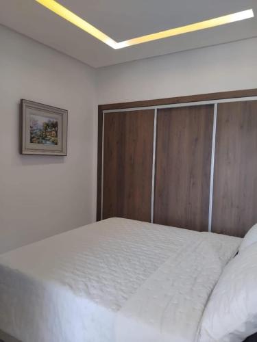 a bedroom with a white bed with a wooden headboard at Hamza Fahim in Kenitra
