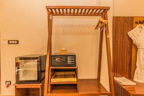 a microwave oven sitting on a stand next to a mirror at Munal and Mayur Resort - Wellness Retreat Pvt Ltd in Tikoli