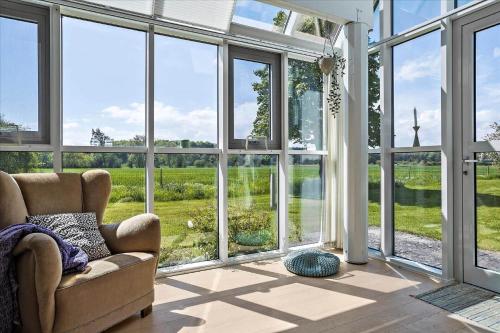 a living room with large windows and a chair at 40117-juelsminde-Gludvej-7 in Juelsminde