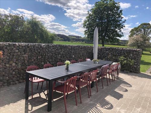a black table with red chairs and a stone wall at 40117-juelsminde-Gludvej-7 in Juelsminde