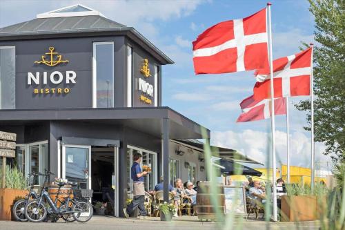 a man standing in front of a restaurant with two flags at 40117-juelsminde-Gludvej-7 in Juelsminde