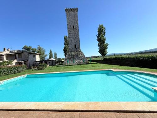 a swimming pool in front of a building with a tower at Fab villa with fenced pool, huge grounds, meditation park, child activity park in Limiti