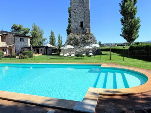 a swimming pool in front of a building with a tower at Fab villa with fenced pool, huge grounds, meditation park, child activity park in Limiti