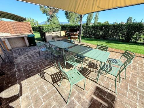 a patio with a table and chairs under an umbrella at Fab villa with fenced pool, huge grounds, meditation park, child activity park in Limiti