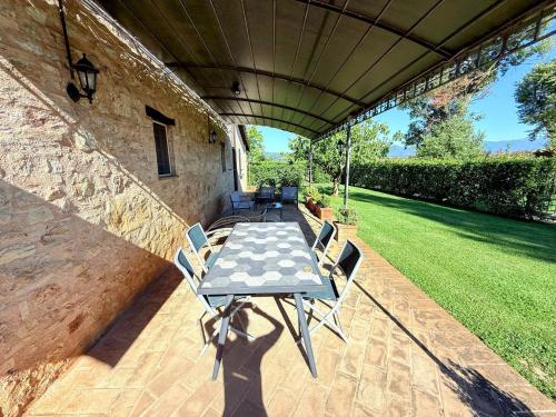 a patio with a table and chairs under a roof at Fab villa with fenced pool, huge grounds, meditation park, child activity park in Limiti