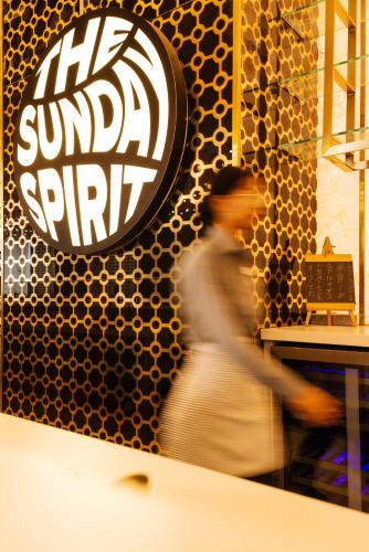 a woman walking past a restaurant with a sign on the wall at Sunday Hotel Chandigarh Zirakpur in Zirakpur