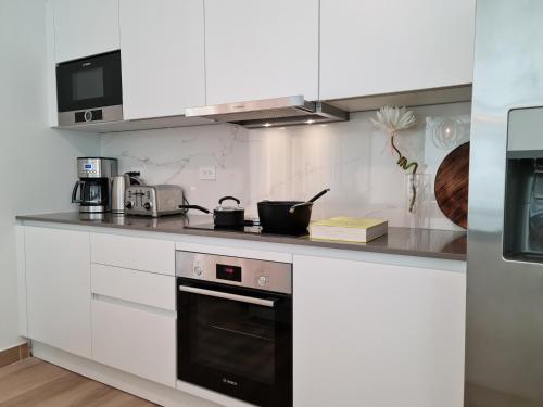 a kitchen with white cabinets and a stove top oven at Tuscany Residence Aruba in Palm-Eagle Beach