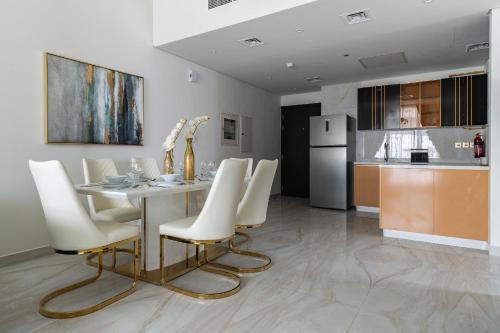 a dining room with a table and white chairs at Simply Comfort Vacation Homes Rental Luxury 3Br Apts with Private Pool in Gemz in Dubai