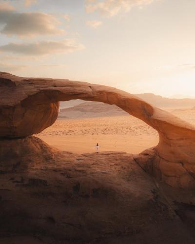 a person standing in an arch in the desert at Wadi Rum, Hala bubbles in Wadi Rum