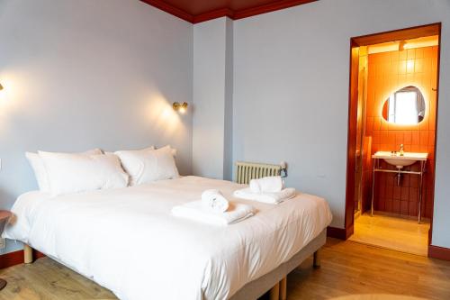 a bedroom with a large white bed with towels on it at Hotel Bleu Soleil in Capbreton