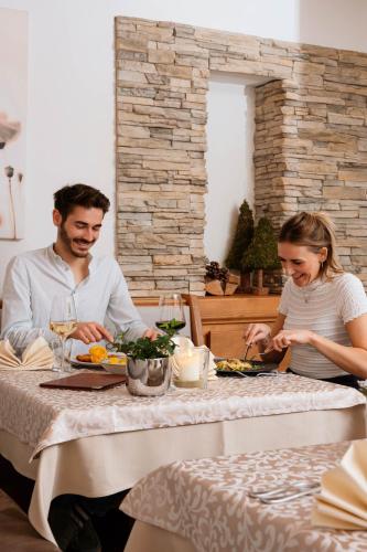a man and woman sitting at a table eating food at Hotel Der Wastlhof - Pools, Spa & eigene Reitschule in Niederau