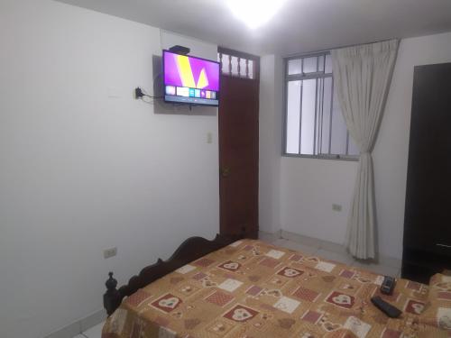 a bedroom with a bed and a tv on the wall at Ambigua Hospedaje in Trujillo