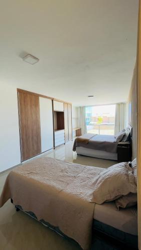 a bedroom with two beds and a large window at Casa Grande Angra de Ipioca in Maceió