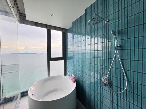 baño con bañera y pared de cristal en Arom Wongamart by David Home, en Norte de Pattaya
