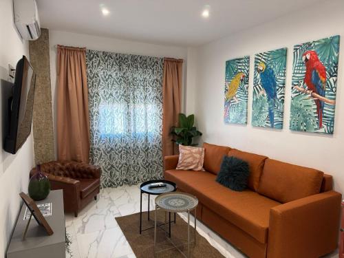 a living room with a couch and two paintings at Apartamento Centro Victor o Victoria in Úbeda