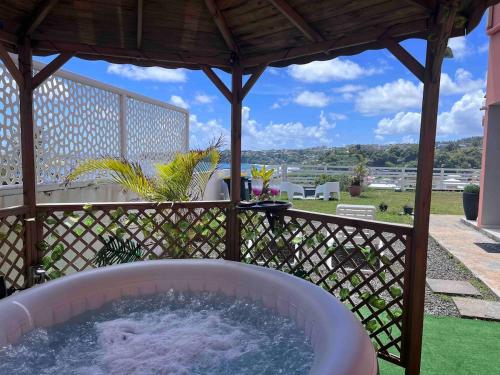 a hot tub in a gazebo on a patio at Les Tourterelles - Appartement vue mer & jacuzzi in Le Lorrain