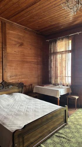 a bedroom with two beds and a table and a window at Wood House Gomi in Ozurgetʼi