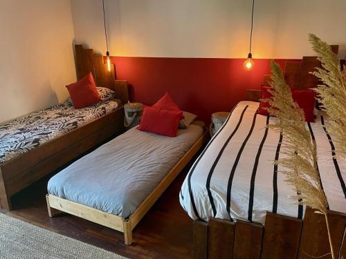 two beds in a room with red walls at Santa Cruz Surf House by Stoke Travel in A dos Cunhados