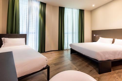 two beds in a room with green curtains at Hotel degli Arcimboldi in Milan