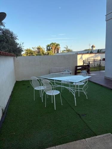 a patio with a table and chairs on the grass at Baia Monoi in Siracusa