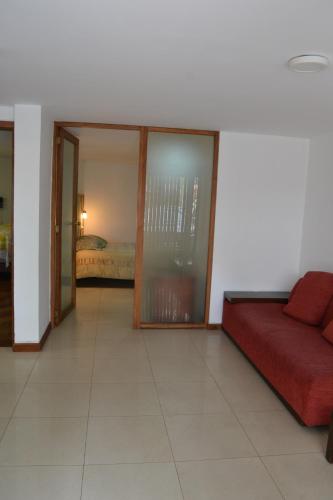 a living room with a red couch and a bedroom at Bamboo Village Place in Tumbaco