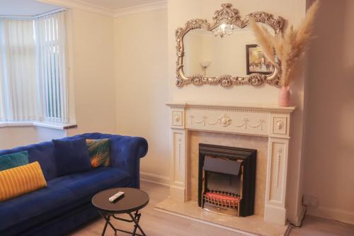 a living room with a blue couch and a fireplace at Beautiful 2 Bedroom house with big Garden & Parking fast wifi, and king size bed in Birmingham