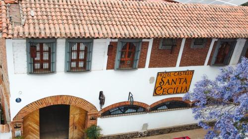a white building with windows and a sign on it at Hotel Santa Cecilia in Tapalpa