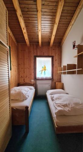 two beds in a room with a window at Nevi Apartment in Folgarida