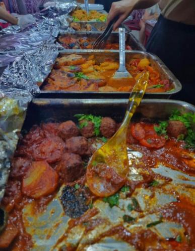 a buffet line with many trays of food with a spoon at Wadi Rum, Hala bubbles in Wadi Rum
