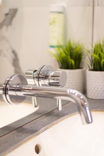 a chrome kitchen faucet on a sink with plants at MOTTO Hotel Gdańsk Riverside OLD TOWN in Gdańsk