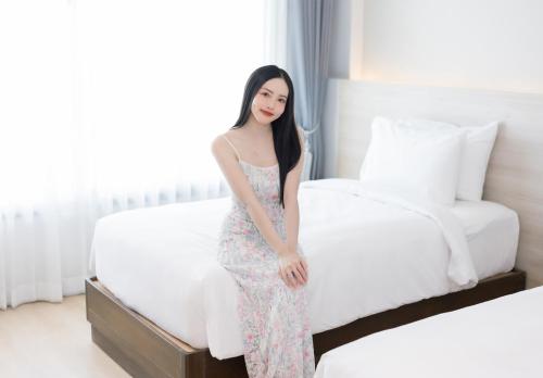 a woman in a dress sitting on a bed at The Horizon Groove Hotel in Ban Khlong