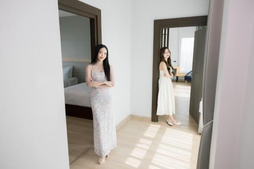 two women standing in a room looking in a mirror at The Horizon Groove Hotel in Ban Khlong