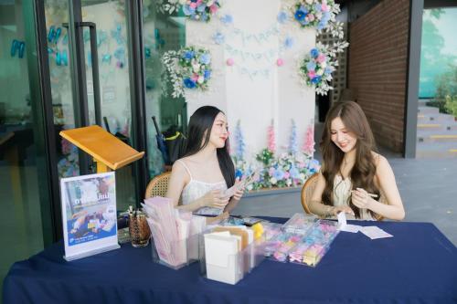 two girls sitting at a table looking at their cell phones at The Horizon Groove Hotel in Ban Khlong