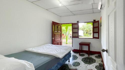 une petite pièce avec un lit et une fenêtre dans l'établissement Rancho Caballo Blanco, à Moyogalpa