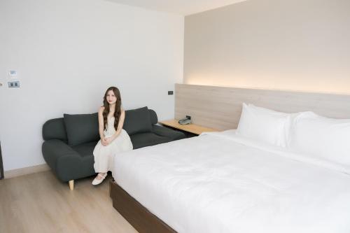 a woman in a hotel room with a bed and a chair at The Horizon Groove Hotel in Ban Khlong