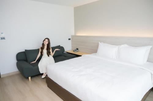 a woman in a hotel room with a bed and a couch at The Horizon Groove Hotel in Ban Khlong
