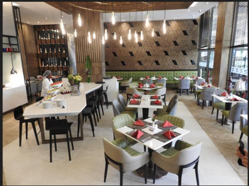 a restaurant with tables and chairs and a person eating at Four Points By Sheraton Nairobi Hurlingham in Nairobi