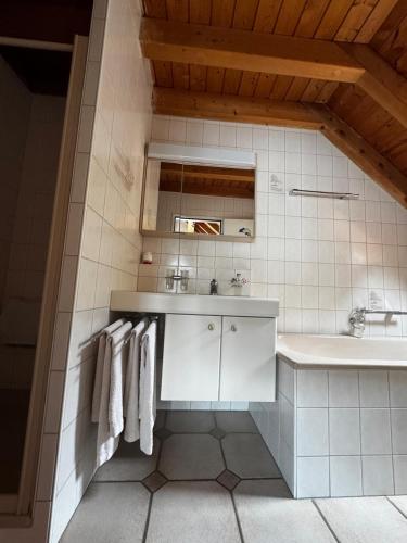 a white bathroom with a sink and a tub and towels at Dachwohnung in Flughafennähe in Kloten