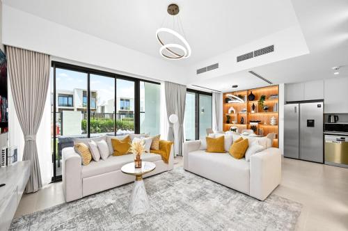 a living room with two white couches and yellow pillows at Golden Stays - Elegant 4BR Escape I Desert Light & Serene Views in Dubai