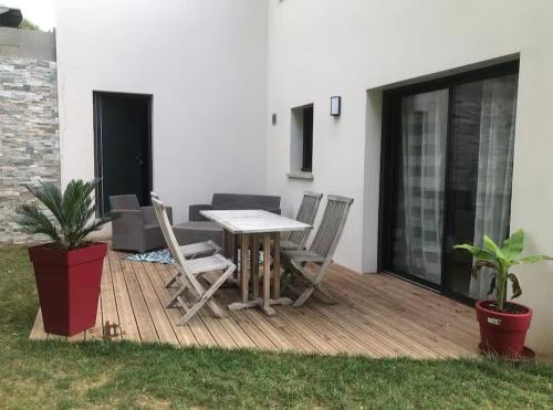 a wooden deck with a table and chairs on it at Le Lotus Oasis des Pins avec piscine in Labenne