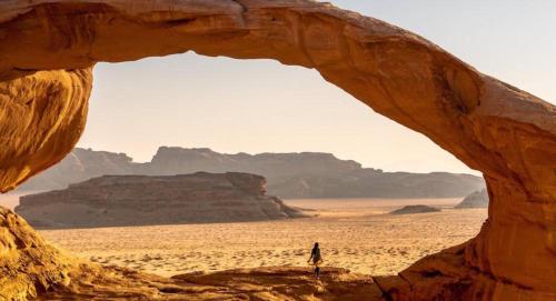 a person walking through an arch in the desert at Wadi Rum, Hala bubbles in Wadi Rum