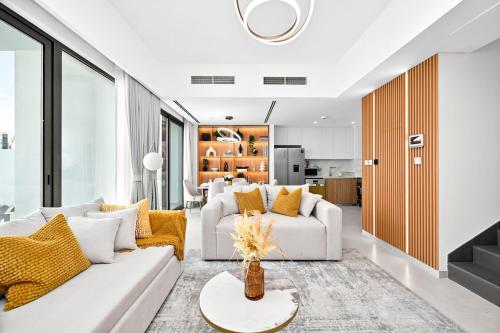 a living room with white furniture and yellow pillows at Golden Stays - Elegant 4BR Escape I Desert Light & Serene Views in Dubai