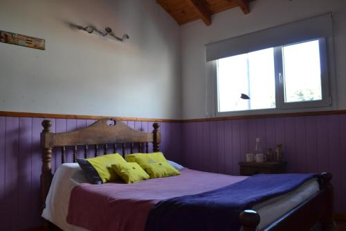a bedroom with a bed with yellow pillows and a window at Casa Hábitat - Habitaciones en casa compartida con baño privado in San Martín de los Andes