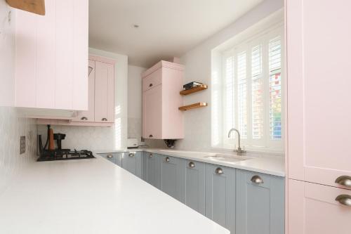 a kitchen with white cabinets and a sink and a window at The PINK House , FREE Parking , 3 Bedrooms , Garden , close to M4 and countryside! in Rogerstone
