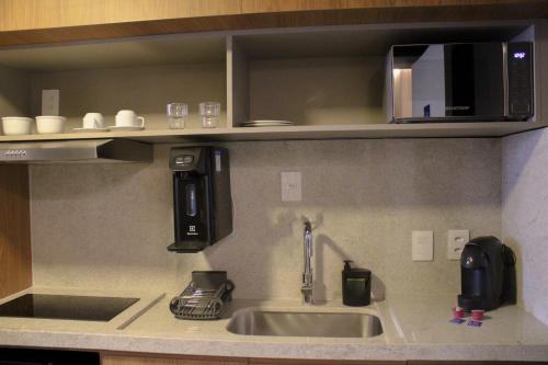 a kitchen with a sink and a microwave at Roomo Transamerica Goiânia Orion in Goiânia