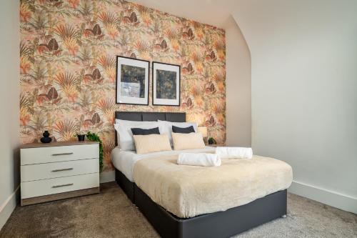 a bedroom with a large bed with a floral wallpaper at Birkenhead Haven - Sleeps 14 - Family and Group Stay in Birkenhead