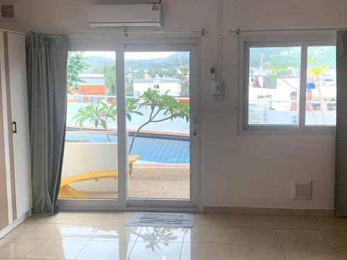 an open glass door with a view of a pool at Kata Hill Sea View Hotel in Kata Beach